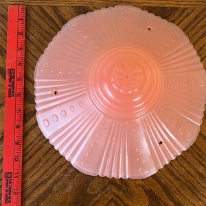 Peut inclure: Un luminaire de plafond en verre rose p&acirc;le avec un bord festonn&eacute; et un motif floral au centre.