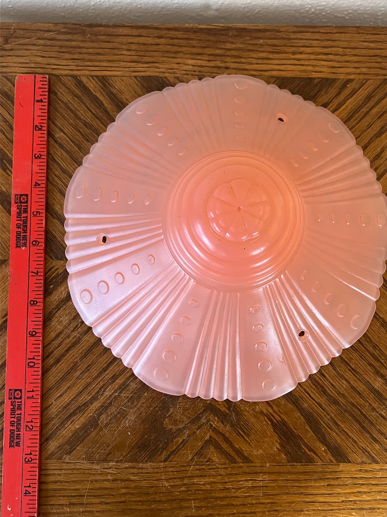 Peut inclure: Un luminaire de plafond en verre rose p&acirc;le avec un bord festonn&eacute; et un motif floral au centre.
