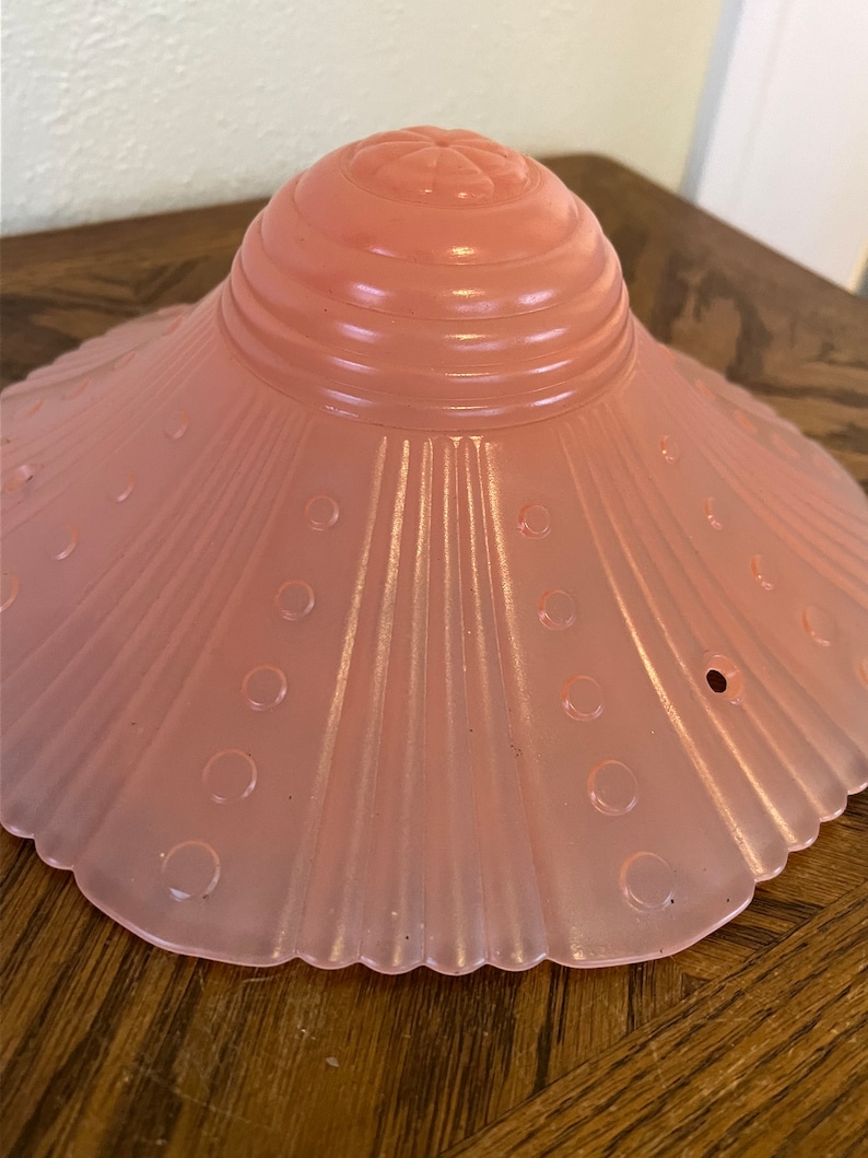 Peut inclure: Un abat-jour de lampe en verre rose p&acirc;le avec un bord festonn&eacute; et un motif textur&eacute; et c&ocirc;tel&eacute;. L'abat-jour a un petit motif floral en relief sur le dessus.