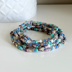 May include: A multi-strand beaded bracelet featuring a mix of turquoise, blue, purple, and silver beads.