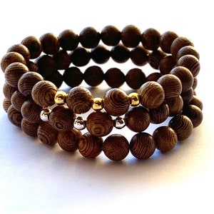 May include: A triple-strand bracelet made of dark brown wooden beads with gold and silver accents.
