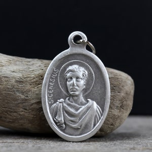 May include: Silver oval pendant featuring a relief image of a man's face. The pendant is inscribed with "S. CENESIUS" on the side.