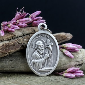 Può includere: Pendente ovale in argento con una raffigurazione di Sant'Andrea che tiene una croce. Il pendente ha incisa la scritta "St. Andrew".
