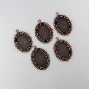 May include: Five copper-toned metal oval pendant trays with ornate edges. Each tray has a smooth, dark brown interior.