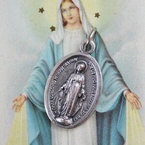 May include: Silver oval pendant with a depiction of the Virgin Mary and the text "O Mary Conceived Without Sin Pray For Us Who Have Recourse To Thee".