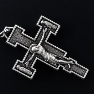 Op de afbeelding: Zilveren kruis hanger met een gedetailleerd ontwerp met een figuur van Jezus Christus aan het kruis. Het kruis heeft een decoratieve rand en de inscriptie "INRI" is zichtbaar.