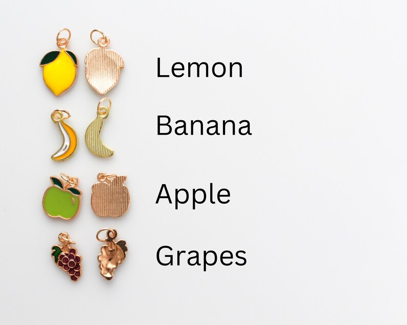 Pu&ograve; includere: Un set di ciondoli in metallo dorato che raffigurano diversi frutti: un limone, una banana, una mela e dell'uva. Ogni ciondolo ha un anello per essere attaccato a una collana, un braccialetto o un altro gioiello.