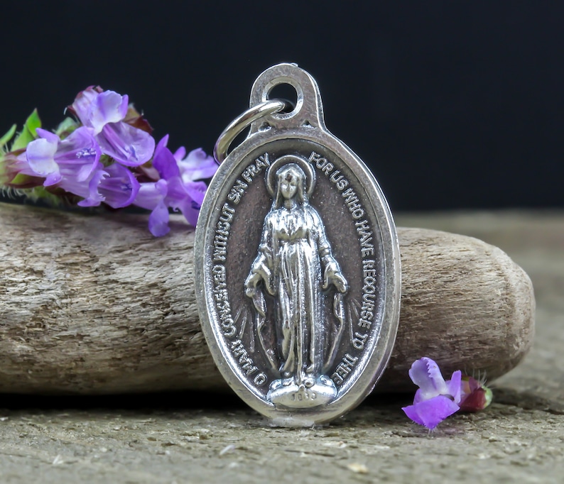 May include: Silver pendant featuring a depiction of the Virgin Mary with the inscription "O Mary Conceived Without Sin Pray For Us Who Have Recourse To Thee".