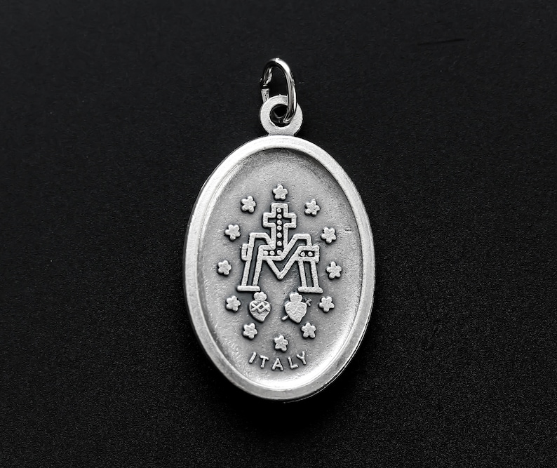 May include: Silver pendant with a detailed image of the Virgin Mary and the words "ITALY" on the bottom.