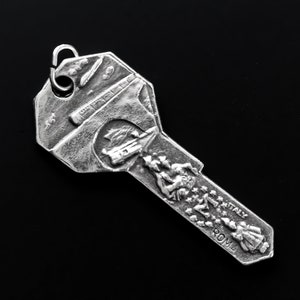 May include: Silver key charm with a detailed design of the Colosseum in Rome, Italy. The charm features a small ring at the top for attaching to a keychain or necklace.