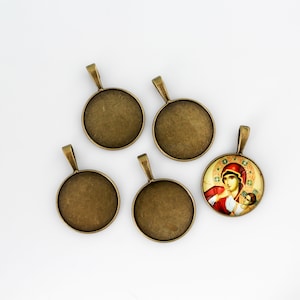 May include: Five round metal pendant trays with a bronze finish. Four trays are blank and one tray features a colorful image of a woman and child.