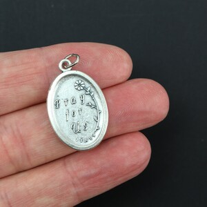 May include: Silver oval charm with the words "Pray for Us" and a small flower design. The charm is made in Italy.
