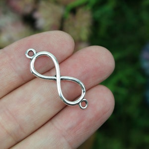 May include: Silver infinity charm with two jump rings for attaching to jewelry or other crafts.