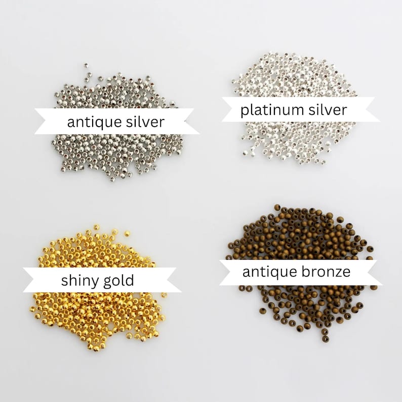 May include: Four piles of small round beads arranged in a grid. The top left pile is labeled antique silver, the top right is labeled platinum silver, the bottom left is labeled shiny gold, and the bottom right is labeled antique bronze.