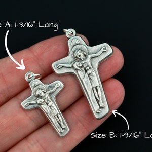 May include: Two silver crucifix pendants, one measuring 1-3/16 inches long and the other measuring 1-9/16 inches long.