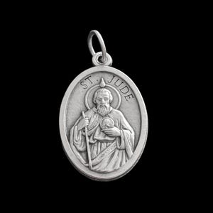 Op de afbeelding: Zilveren ovaalvormige hanger met een afbeelding van de Heilige Judas Thaddeus. De hanger heeft de woorden "ST. JUDE" en een halo rond het hoofd van de heilige.