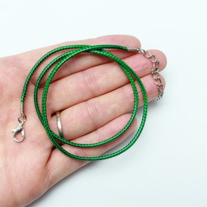 May include: A green cord necklace with a silver clasp and extender chain.