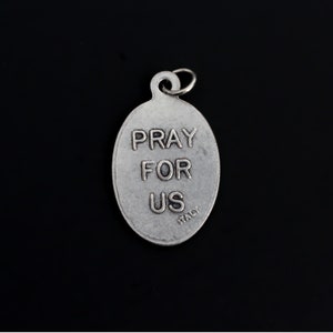 May include: Silver oval charm with the words "Pray for Us" and "Italy" inscribed on it.