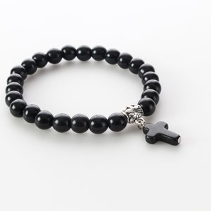 May include: Black beaded bracelet with a silver cross charm. The beads are round and smooth.