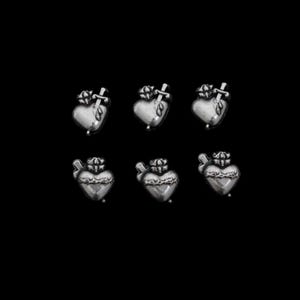 May include: Six silver-toned heart-shaped charms with a crown and a sword piercing the heart. The charms are arranged in two rows of three against a black background. The hearts have a detailed, textured design.