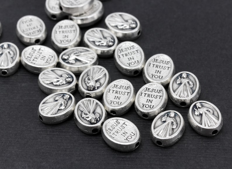 Puede incluir: Una colecci&oacute;n de cuentas ovaladas de plata con las palabras "Jes&uacute;s conf&iacute;o en ti" grabadas en cada cuenta. Las cuentas tienen una imagen en relieve de Jes&uacute;s en el centro.