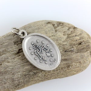 May include: Silver oval pendant with a black and white image of the Virgin Mary and the words "ITALY" on the bottom.
