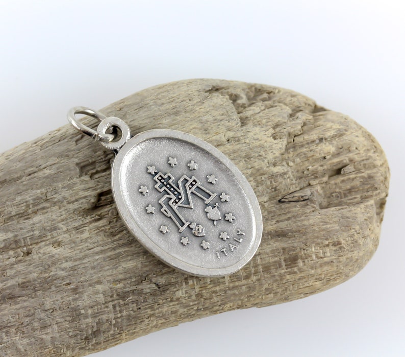 May include: Silver oval pendant with a black and white image of the Virgin Mary and the words "ITALY" on the bottom.