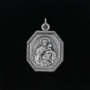 May include: Silver pendant with an octagonal frame featuring a relief image of the Virgin Mary holding a baby Jesus.