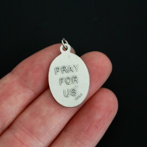May include: Silver oval pendant with the words "Pray for Us" and "Italy" engraved on the back.