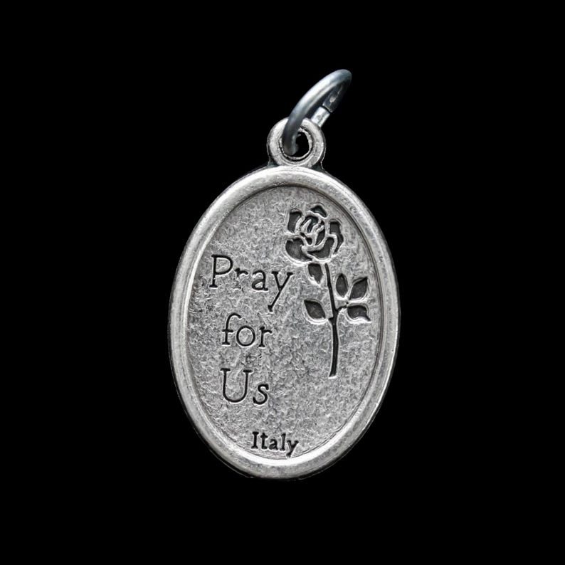 Op de afbeelding: Zilveren ovale hanger met de woorden "Pray for Us" en een roosontwerp. De hanger heeft ook de tekst "Italy" aan de onderkant.