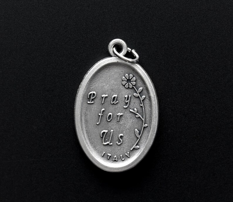 May include: Silver oval charm with the words "Pray for Us" and a small flower design. The charm is made in Italy.