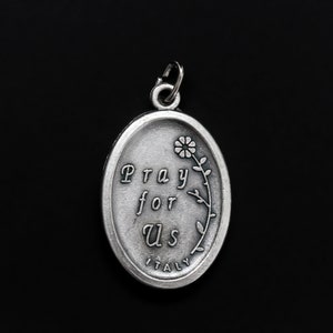 May include: Silver oval pendant with the words "Pray for Us" and a small flower design. The pendant also says "Italy" at the bottom.