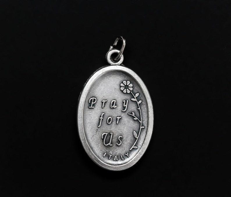 May include: Silver oval pendant with the words "Pray for Us" and a small flower design. The pendant also says "Italy" at the bottom.