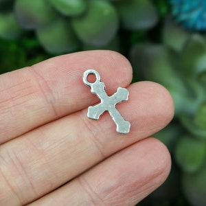May include: Silver-toned metal cross charm with a loop at the top for attaching to jewelry or crafts.