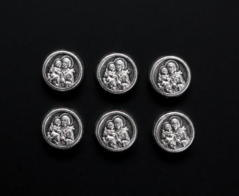 May include: Six silver-toned metal medallions with images of a mother and child. Each medallion features a different image of the mother and child.