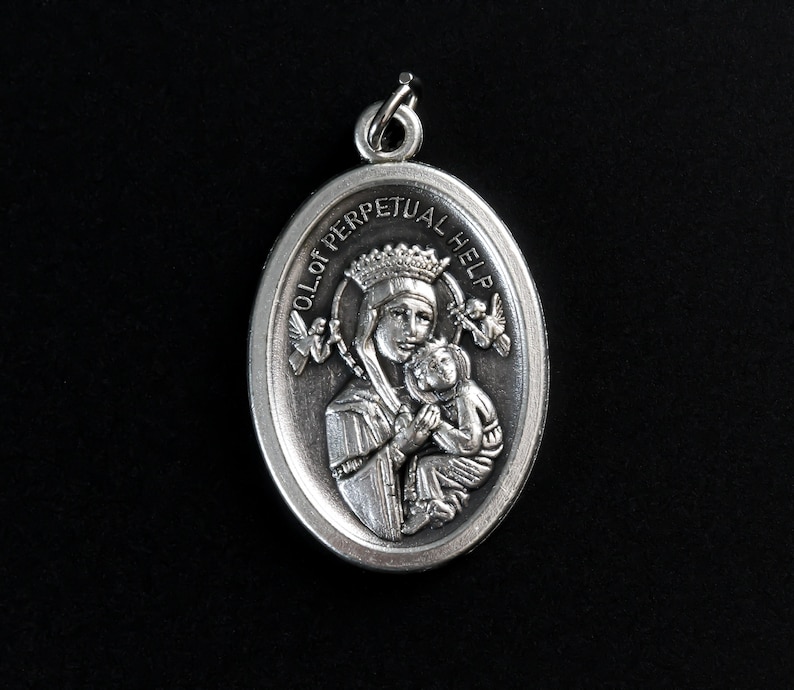 Op de afbeelding: Zilveren ovale hanger met een afbeelding van Onze-Lieve-Vrouw van de Onbevlekte Ontvangenis die een kind vasthoudt. De hanger heeft de woorden "OL of Perpetual Help" rond de rand gegraveerd.