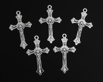May include: Five silver-toned crucifix pendants with a detailed depiction of Jesus Christ. Each cross features the inscription "INRI" at the top and a loop for hanging. The crosses are arranged against a black background.