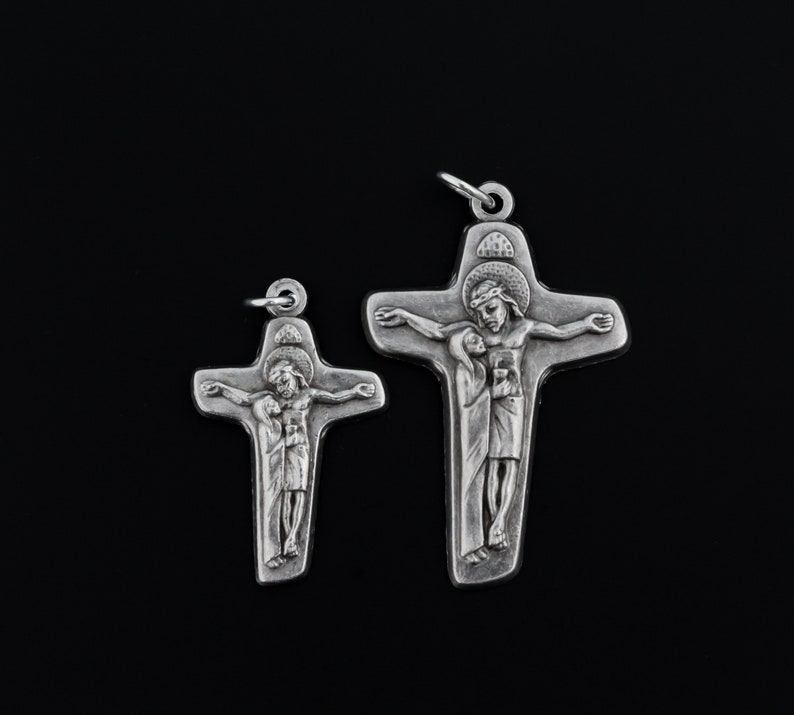 May include: Two silver crucifixes with a depiction of Jesus Christ and Mary. The larger crucifix is about 5 inches tall and the smaller crucifix is about 3 inches tall.