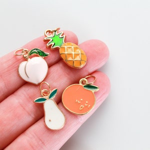 Pu&ograve; includere: Quattro ciondoli dorati a forma di frutta: un ananas, una pesca, un'arancia e una pera. I ciondoli sono smaltati con colori vivaci e hanno un anello dorato per essere attaccati a una collana o un braccialetto.
