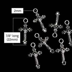 May include: A collection of silver-toned metal crucifix charms featuring a detailed figure of a person. Each charm has a circular jump ring at the top, measuring 2mm in diameter. The total length of each crucifix charm is 7/8 inches or 22mm.