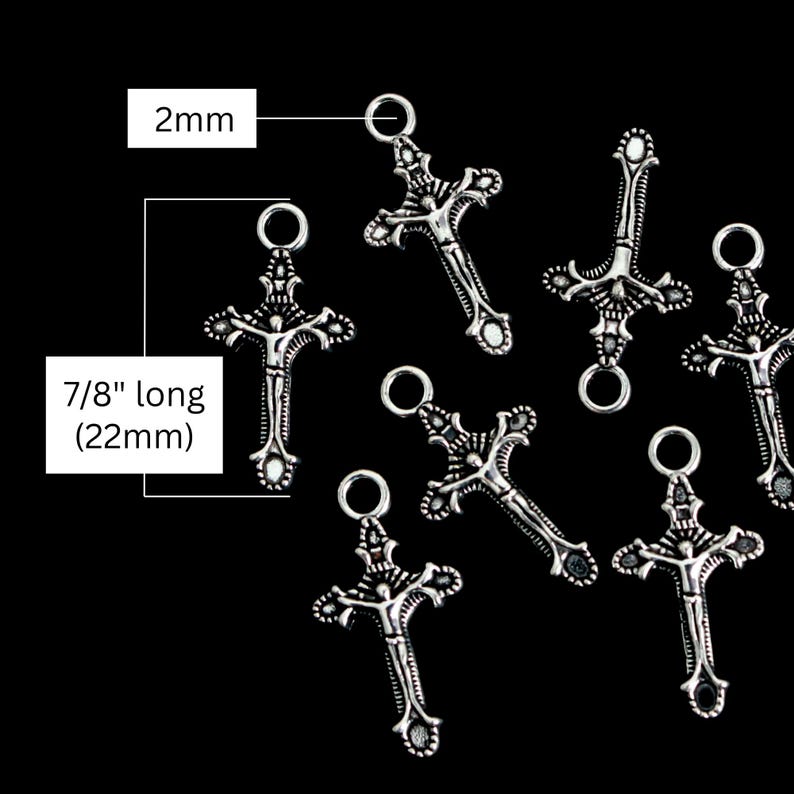 May include: A collection of silver-toned metal crucifix charms featuring a detailed figure of a person. Each charm has a circular jump ring at the top, measuring 2mm in diameter. The total length of each crucifix charm is 7/8 inches or 22mm.