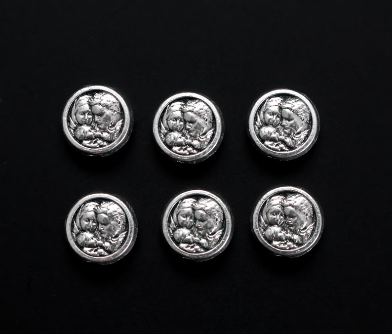 May include: Six silver-toned metal charms featuring an image of two angels embracing. Each charm is round and has a raised design.
