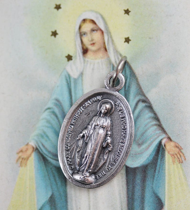 May include: Silver oval pendant with a depiction of the Virgin Mary and the text "O Mary Conceived Without Sin Pray For Us Who Have Recourse To Thee".