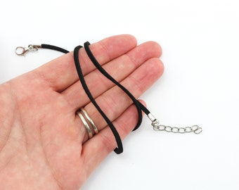 May include: A black suede cord necklace with a silver lobster clasp and a silver chain extension.