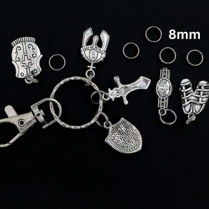 May include: A silver key chain with a variety of charms, including a sword, shield, crown, and helmet. The key chain also includes a silver clasp and several 8mm silver jump rings.