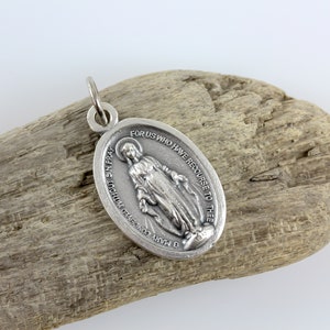 May include: Silver oval pendant with a depiction of the Virgin Mary, holding a rosary. The pendant has the inscription "O Mary conceived without sin pray for us who have recourse to thee".