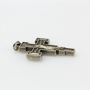 Op de afbeelding: Een zilverkleurige metalen kruis hanger met een gedetailleerde afbeelding van Jezus Christus aan het kruis.