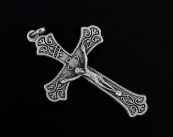 May include: Silver crucifix pendant with an ornate design and a figure of Jesus Christ on the cross.