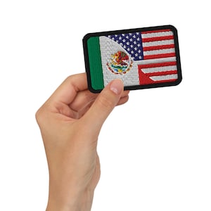 Puede incluir: Parche bordado con un diseño combinado de las banderas mexicana y estadounidense. El parche tiene un borde negro, con la bandera mexicana a la izquierda y la bandera estadounidense a la derecha. La bandera mexicana incluye el emblema nacional.