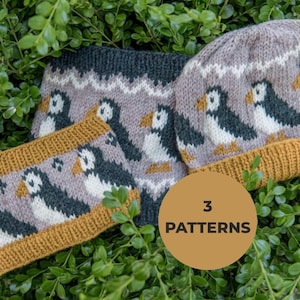 May include: A knitted beanie and a matching neck warmer featuring a repeating pattern of puffin birds in black, white, and orange on a light brown background with dark gray and mustard yellow ribbed edges. A circular label reads 3 PATTERNS.